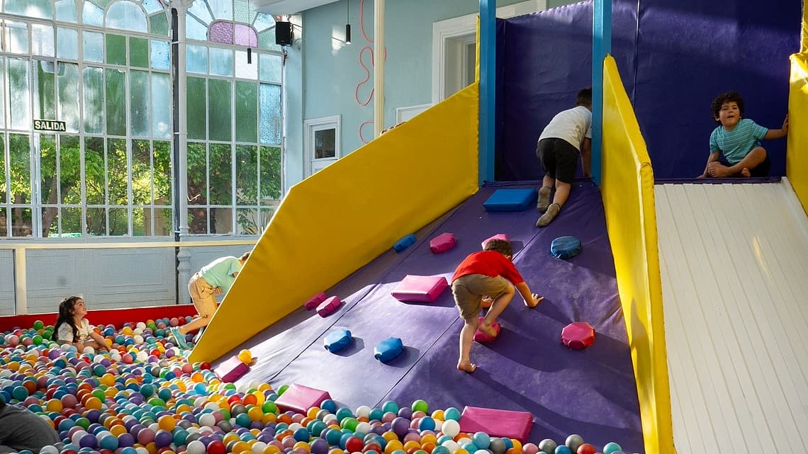 Imagen de pelotero con pelotas y niños jugando